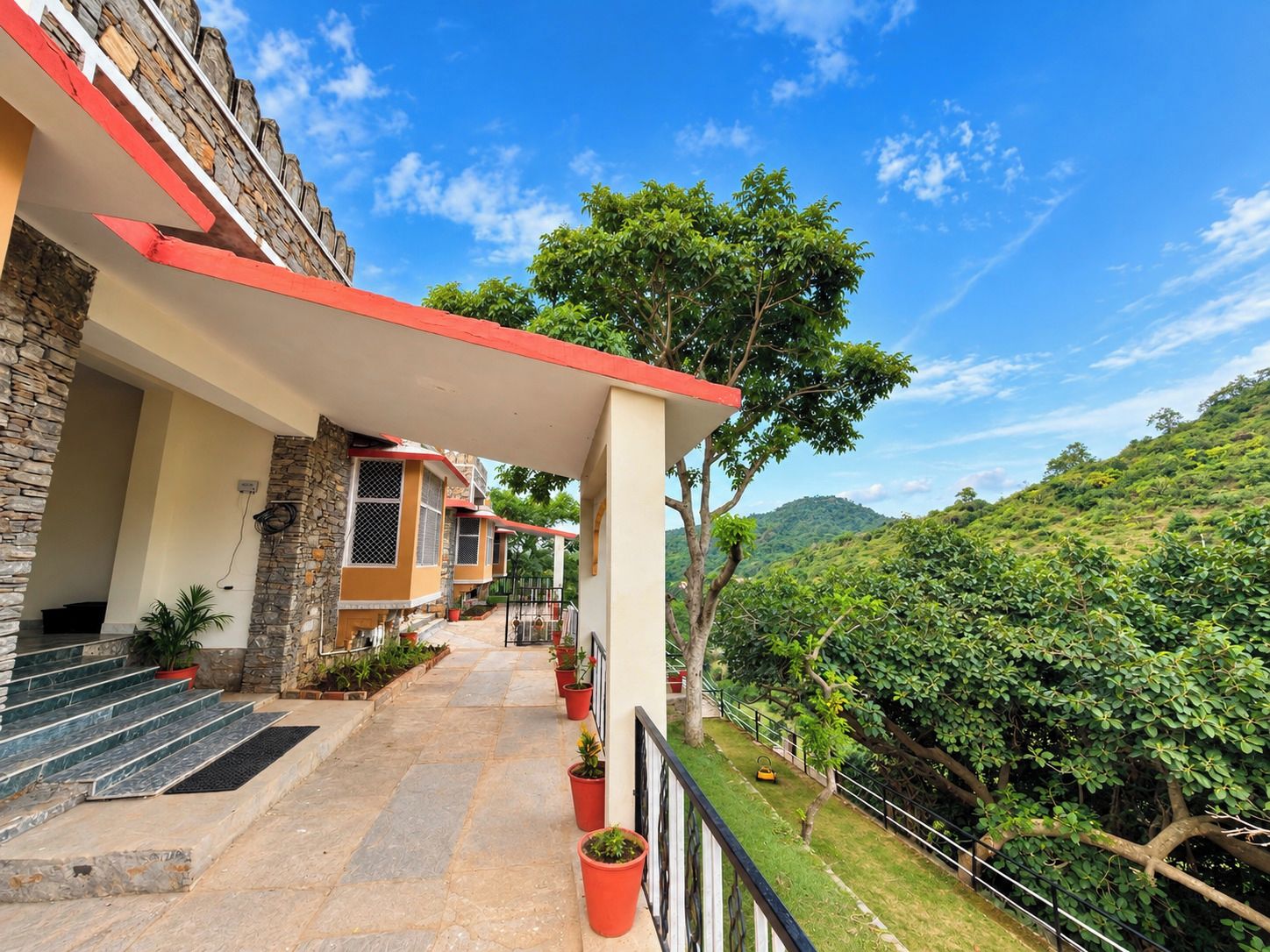 A hotel with a stone facade, a red roof, and a view of a lush green hillside.