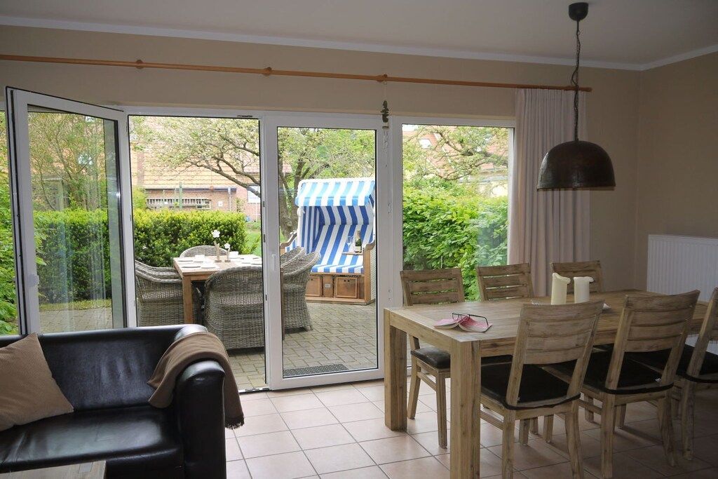 A room with a sliding glass door leading to an outdoor area with a table and chairs, a sofa, and a hanging pendant light.