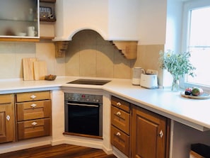 A kitchen with wooden cabinets, a built-in oven, a countertop, and a window. - New Listing (Moos)