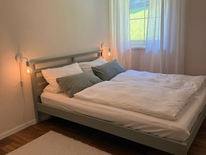A single bed with a wooden frame, white bedding, and two wall-mounted reading lamps. - New Listing (Moos)