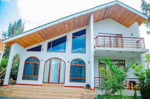 A two-story building with a wooden roof, large windows, and a balcony.