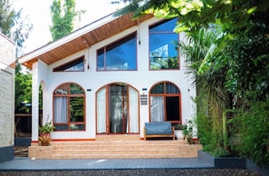 A two-story house with a wooden porch, large windows, and a small garden area.