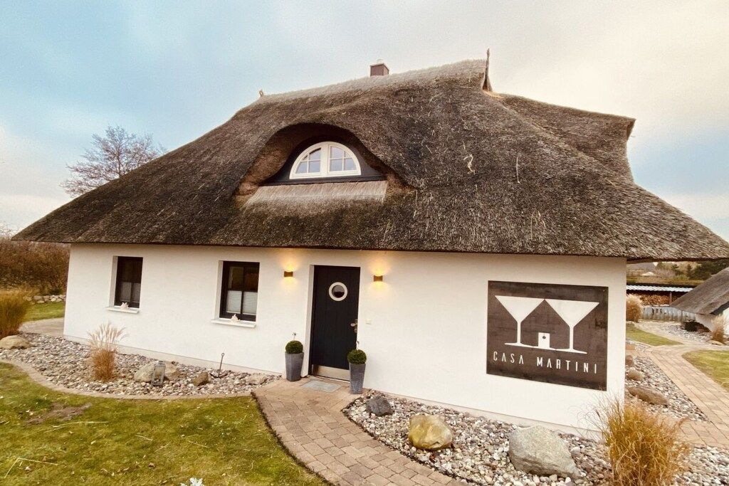 A house with a thatched roof, a black door, and a logo on the side.