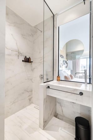 Un bagno con una parete in marmo, un grande specchio e una zona doccia.