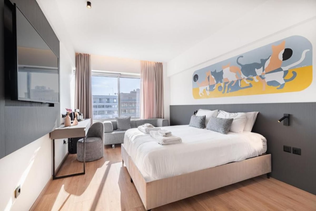 Una moderna camera d'albergo con un ampio letto, una scrivania e vista sulla città.