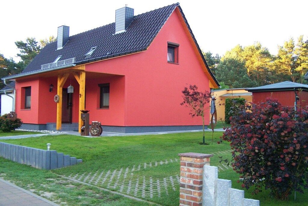 A red house with a sloped roof, a small porch, and a brick chimney.