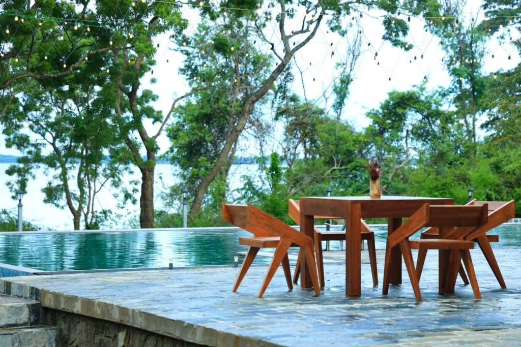 Ein Außenbereich mit Sitzgelegenheit, Pool, Bäumen und Blick auf das Wasser.