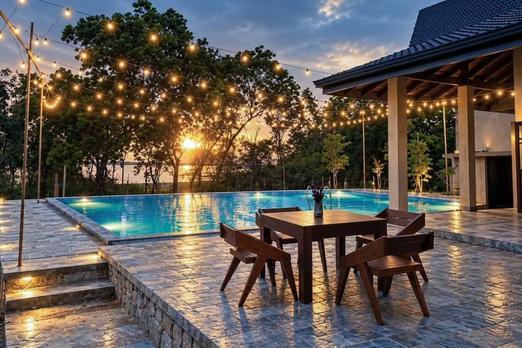 Ein Swimmingpool mit einer Steinterrasse, umgeben von Bäumen und Lichterketten.