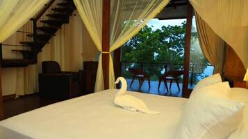 Ein Schlafzimmer mit einem Bett, einer Schwan-Dekoration, einer Treppe und einem Balkon mit Stühlen.