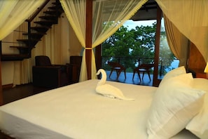 A bedroom with a bed, a swan decoration, a staircase, and a balcony with chairs. - Safari Lake Resort Udawalawe (Udawalawe)