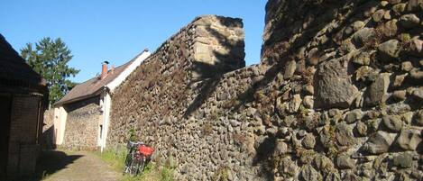 Una estrecha calle empedrada con muros de piedra y un edificio con tejado inclinado.