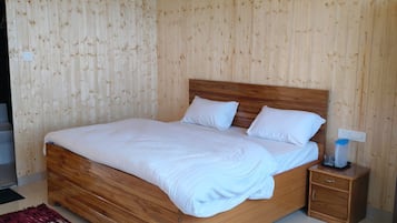 A wooden-paneled bedroom with a wooden bed, a nightstand, and a red and white rug.