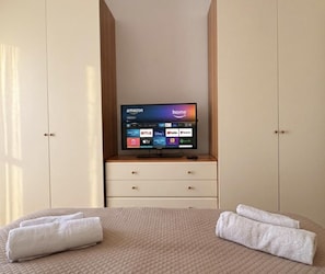 Une chambre d’hôtel comprenant un lit, un téléviseur posé sur un meuble et diffusant divers services de streaming, ainsi qu’une armoire.