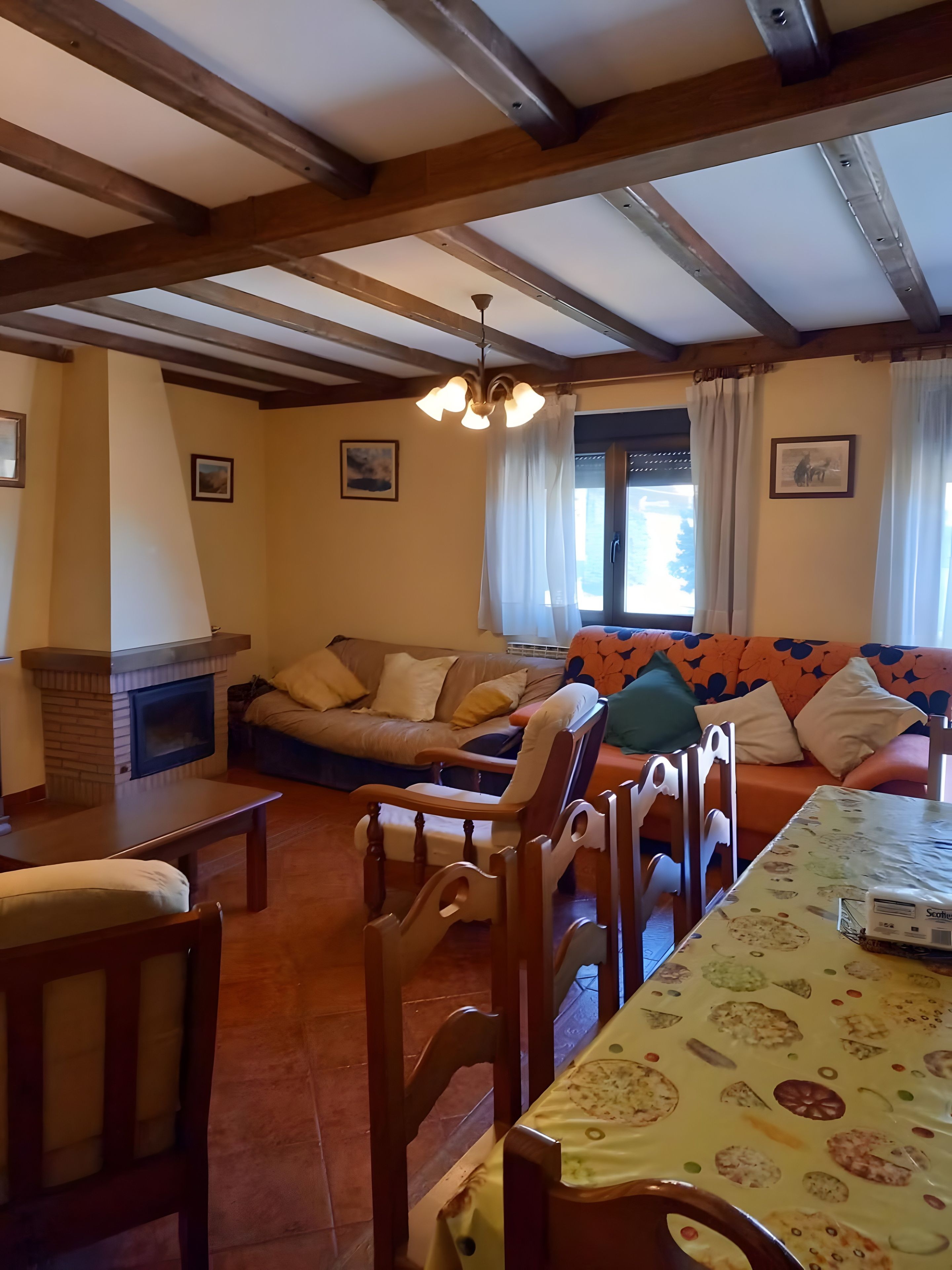 Un salon chaleureux avec une cheminée, des meubles en bois et une nappe à motifs.