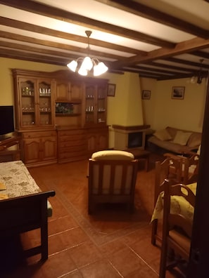 A cozy living room with a wooden cabinet, a dining table, and a comfortable sofa. - Country House 'Casa Rural La Cerra' with Mountain View, Shared Garden and Wi-Fi (Navalguijo)