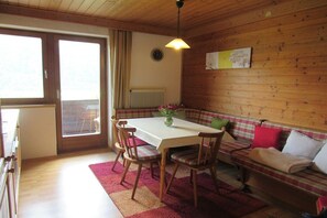 A dining area with a table and chairs, a bench, a radiator, and a window.