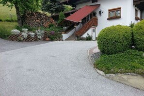 A house with a red roof, a stone wall, and a gravel driveway.