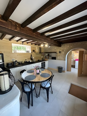 Una cocina moderna con una isla central, vigas de madera y una pared de piedra.