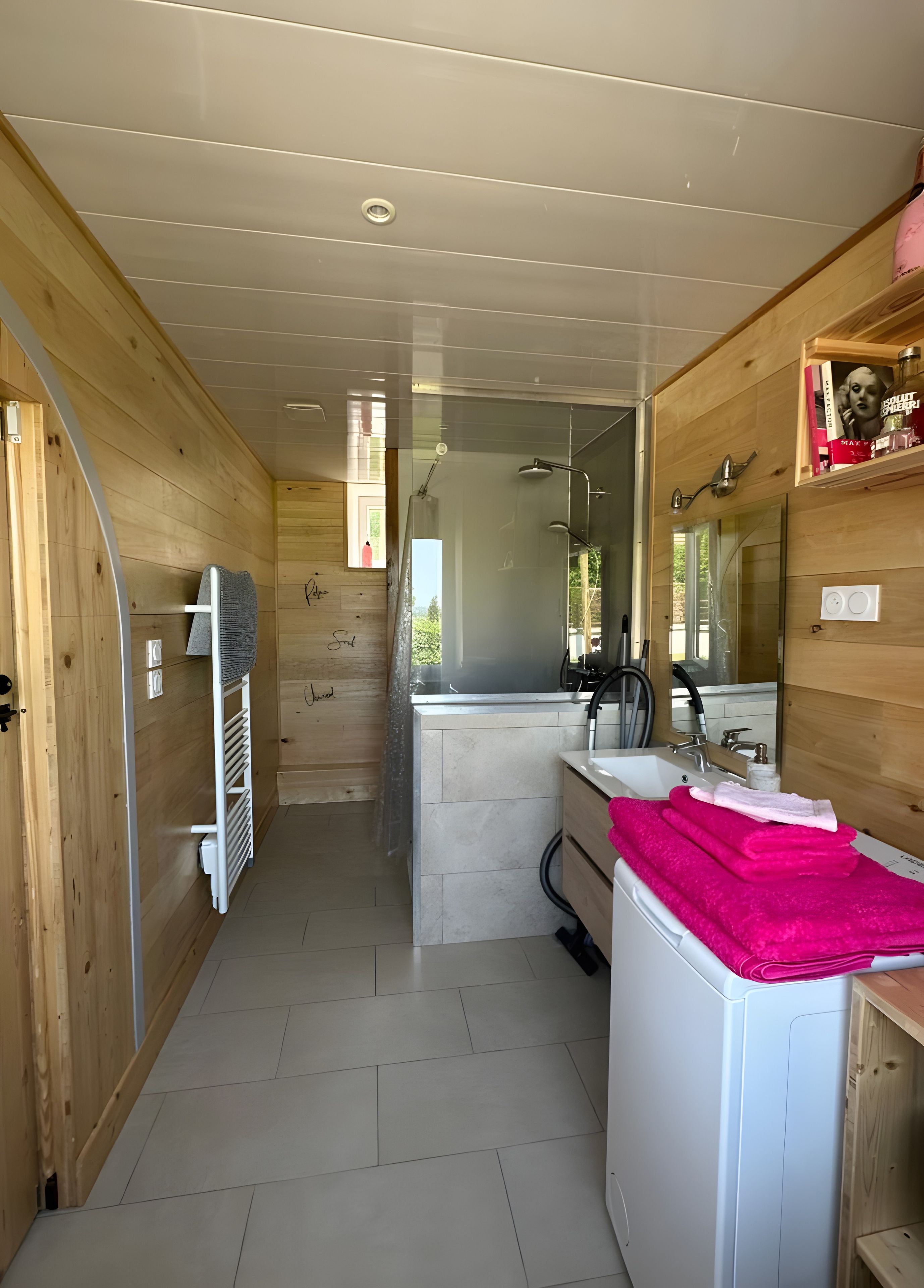 Een moderne badkamer met een douche, wastafel en houten wanden.