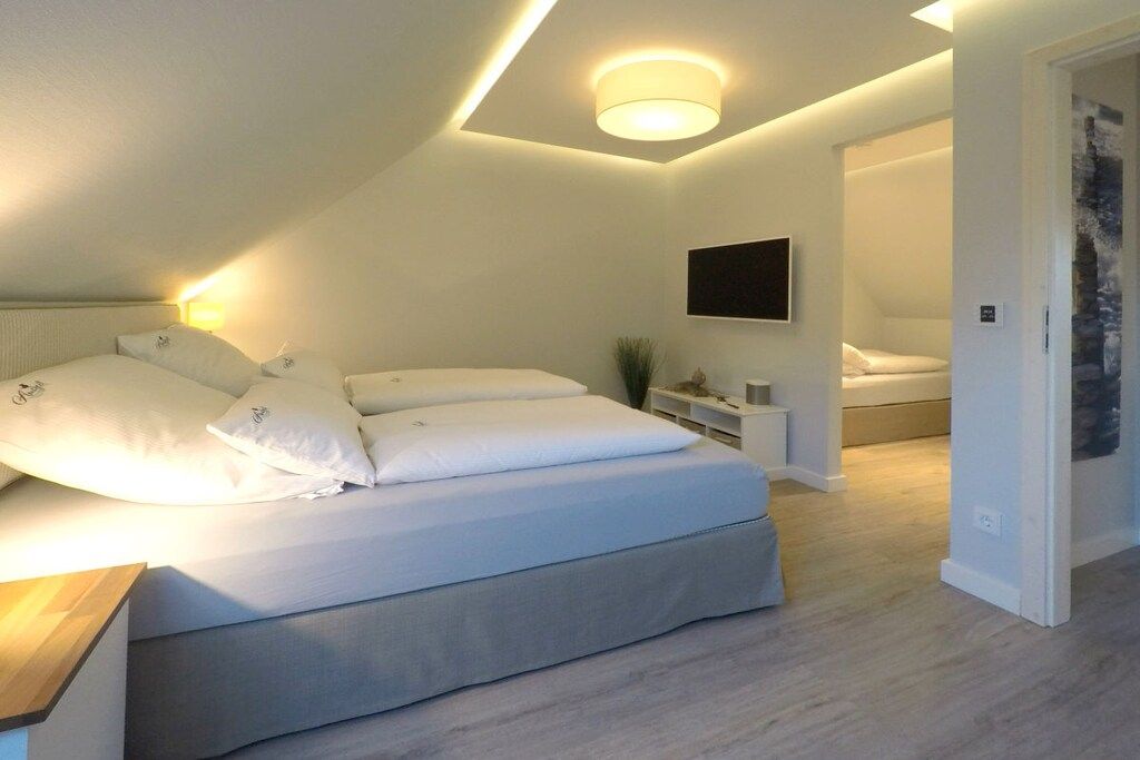 A modern bedroom with a bed, bedside table, and a mounted TV.