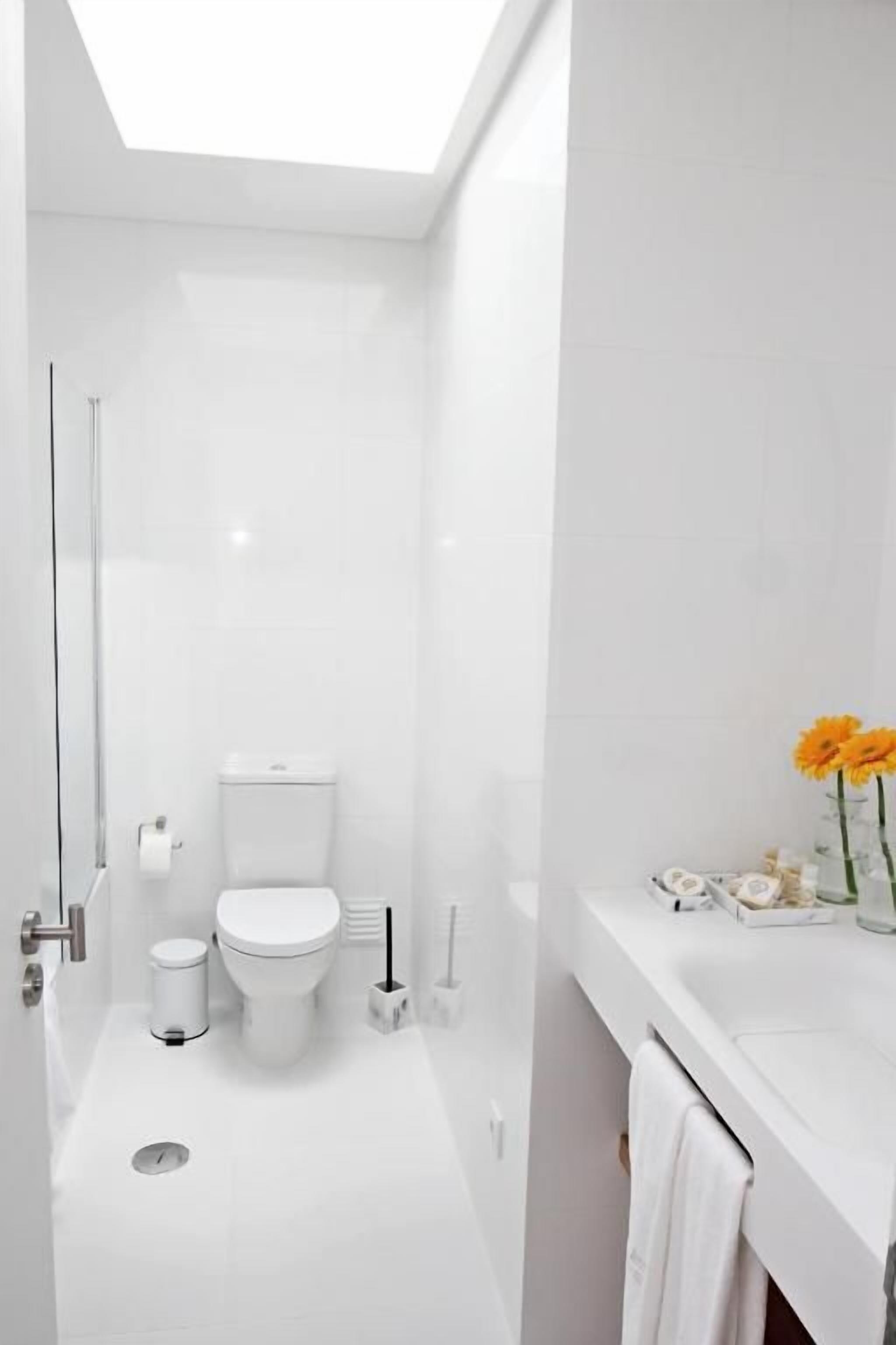 Un bagno moderno con una finestra a lucernario, un water, un lavandino e una zona doccia.