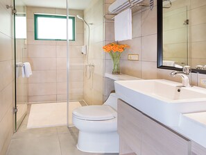Een moderne badkamer met een douchecabine van glas, een wit toilet en een wastafel met spiegel erboven.