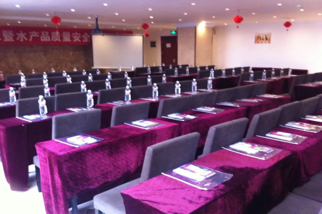 A conference room with rows of tables, each with a water bottle and a nameplate.