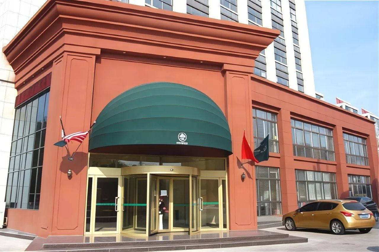 A hotel entrance with a revolving door, a flag, and a car parked outside.