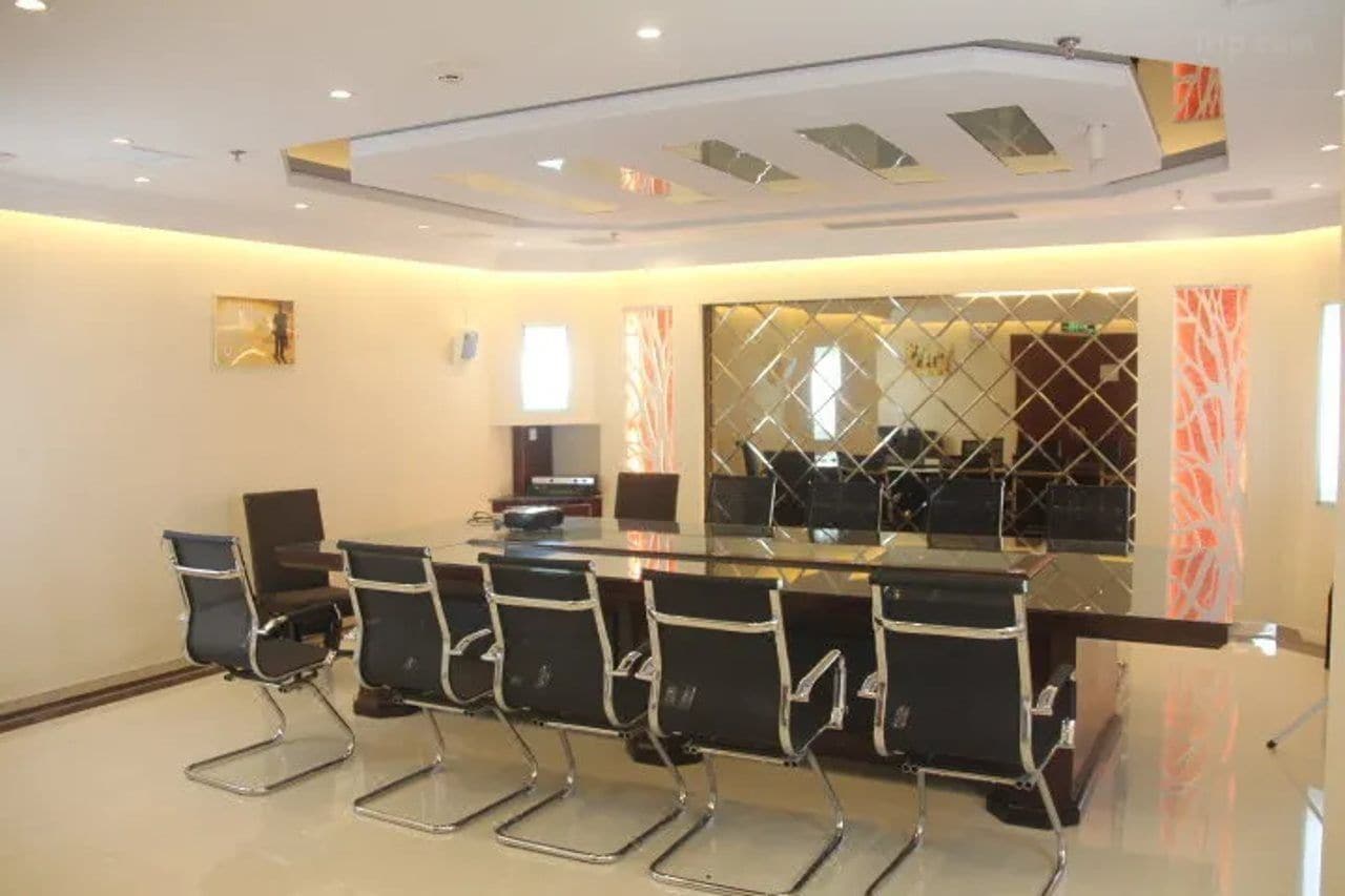A conference room with a glass table and black chairs, a modern ceiling design, and a decorative wall panel.