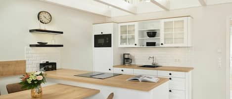 A modern kitchen with white cabinetry, a wooden countertop, and a built-in oven.