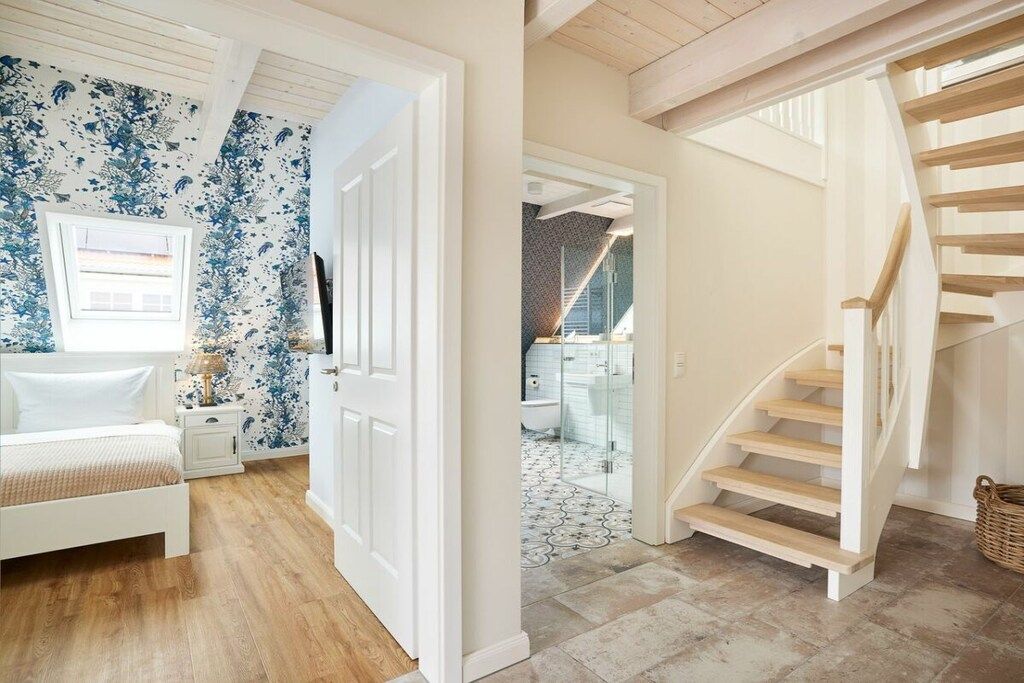 A bedroom with a bed, a nightstand, and a door leading to a bathroom.