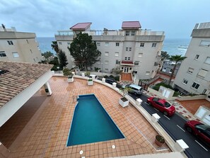 A residential building with a swimming pool, a view of the sea, and a tiled patio area. - New Listing (Benalmádena)