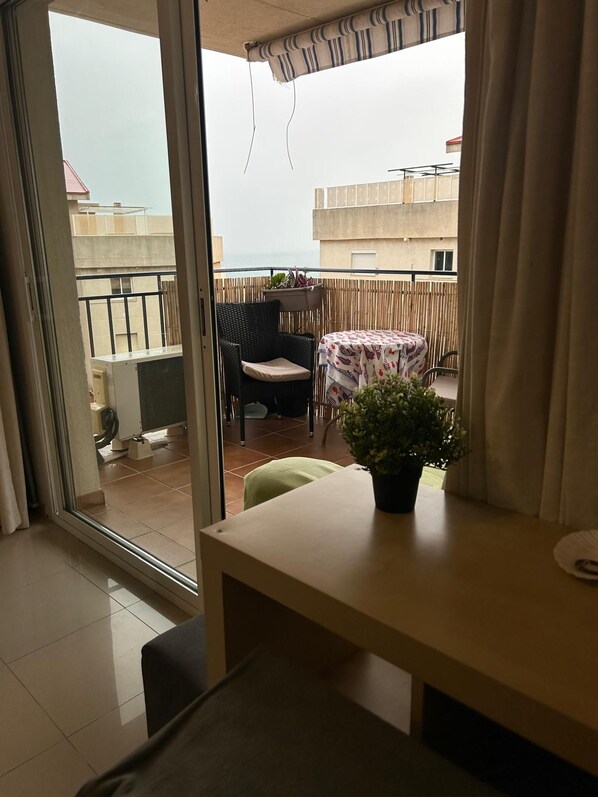 A balcony with a table, chairs, a potted plant, and a view of buildings. - New Listing (Benalmádena)