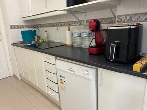 A kitchen with white cabinets, a black countertop, a red coffee maker, a black refrigerator, and a dishwasher. - New Listing (Benalmádena)
