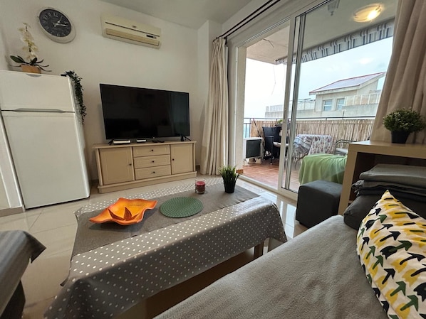 A living room with a television, a dining table with a polka dot tablecloth, and a sofa with a patterned cushion.
