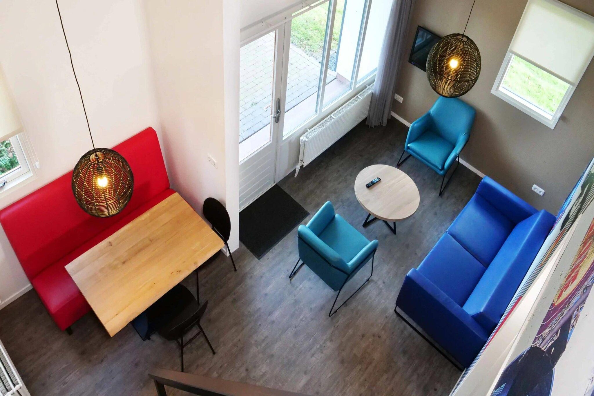 Et moderne interiør med en rød sofa, blå lænestole, et træbord og et rundt sofabord.