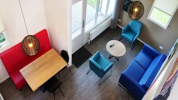 Et moderne interiør med en rød sofa, blå lænestole, et træbord og et rundt sofabord.