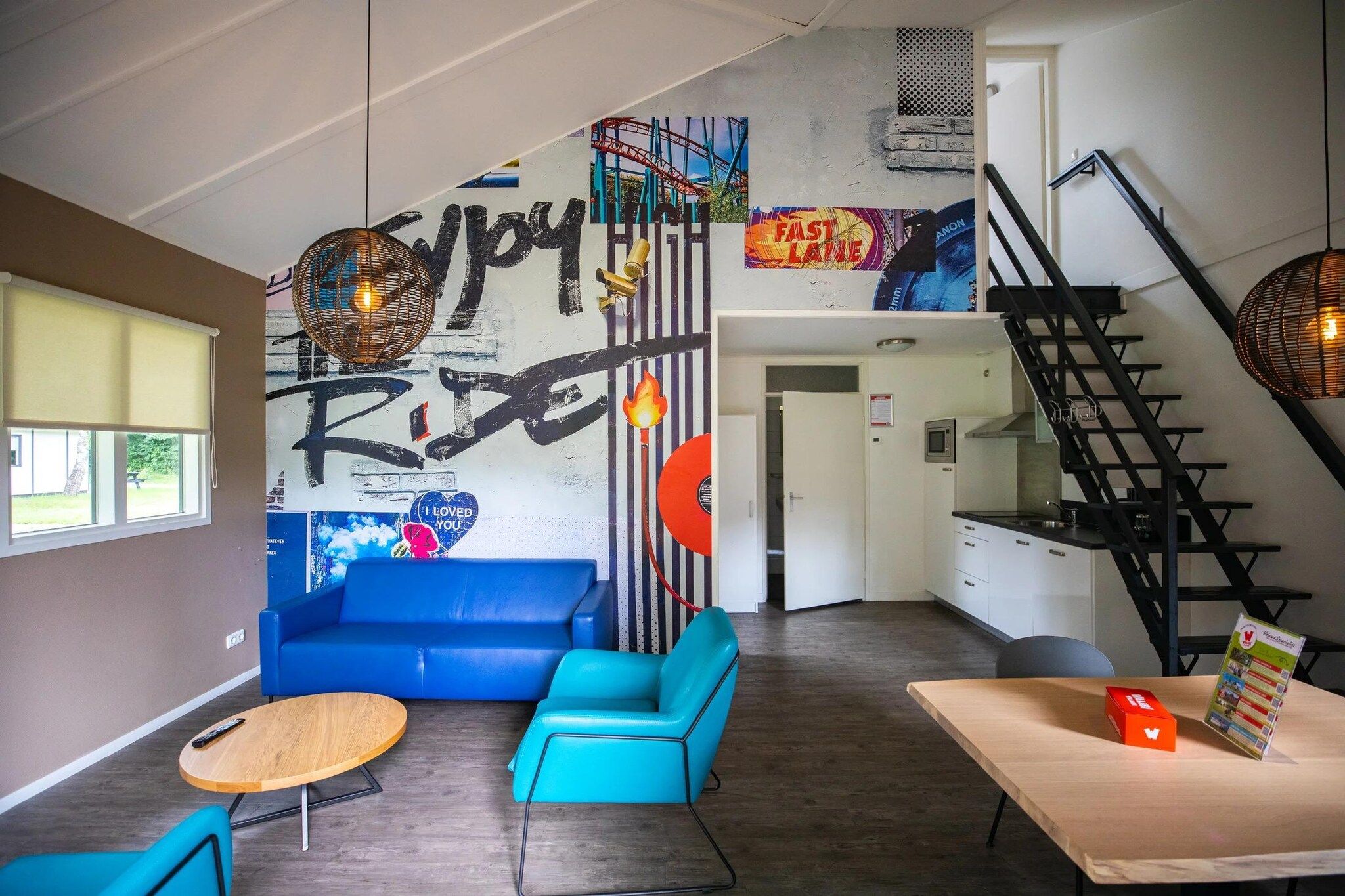 A modern interior with a blue sofa, a wooden table, and a staircase.