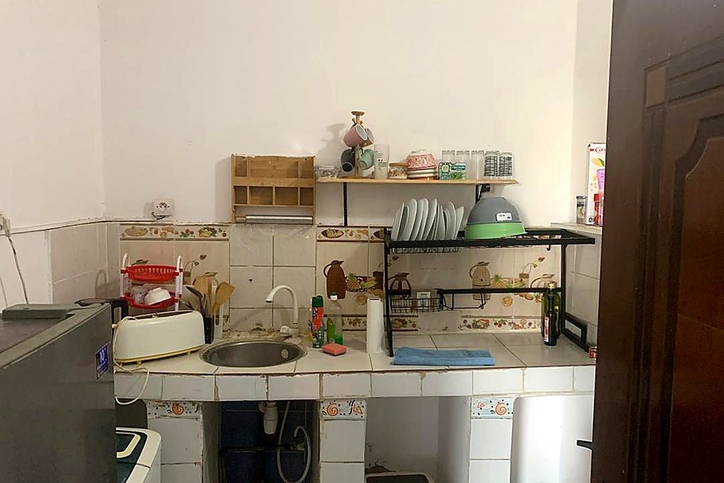 Une petite cuisine équipée d’un évier, d’un grille-pain et d’un four à micro-ondes. Une étagère au-dessus de l’évier permet de ranger divers ustensiles de cuisine.