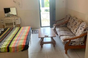 Ein Zimmer mit einem Bett, einem Schlafsofa, einem Holztisch und einem Schreibtisch mit Spiegel.