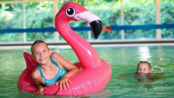 A person in a swimming pool using a pink flamingo float.