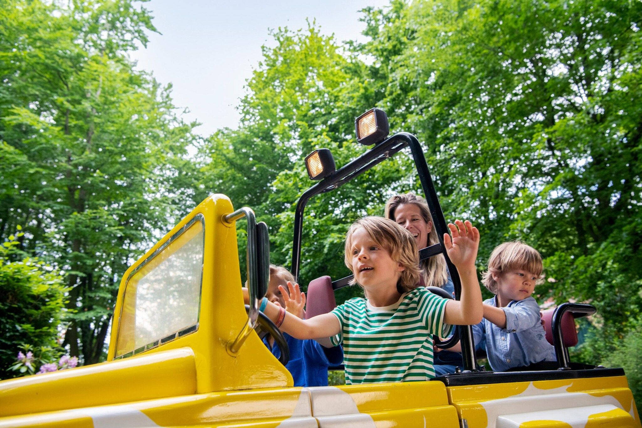 Ein gelbes Fahrzeug mit Fahrgästen, umgeben von viel Grün.