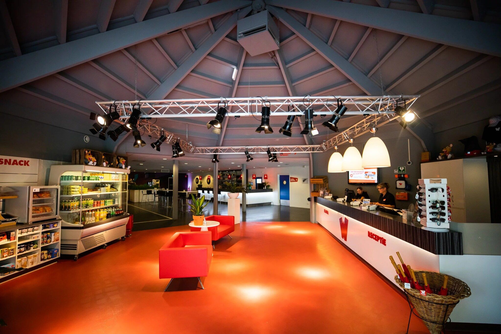 A spacious indoor area with a high ceiling, multiple seating areas, and a reception desk.