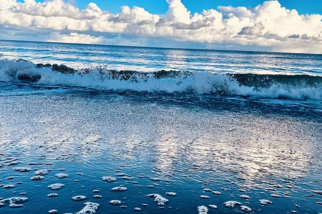 A beach with waves and a clear sky.