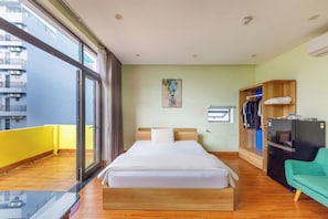 A hotel room with a bed, a wardrobe, a desk, and a view of the outside. - Beauty Large Balcony Kingbed Studio Apartment with AC and Full Kitchen Da Nang (Đà Nẵng)