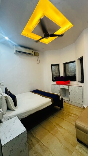 Ein Schlafzimmer mit Bett, Nachttischen, einem Schreibtisch, einer Klimaanlage und einem Deckenventilator.