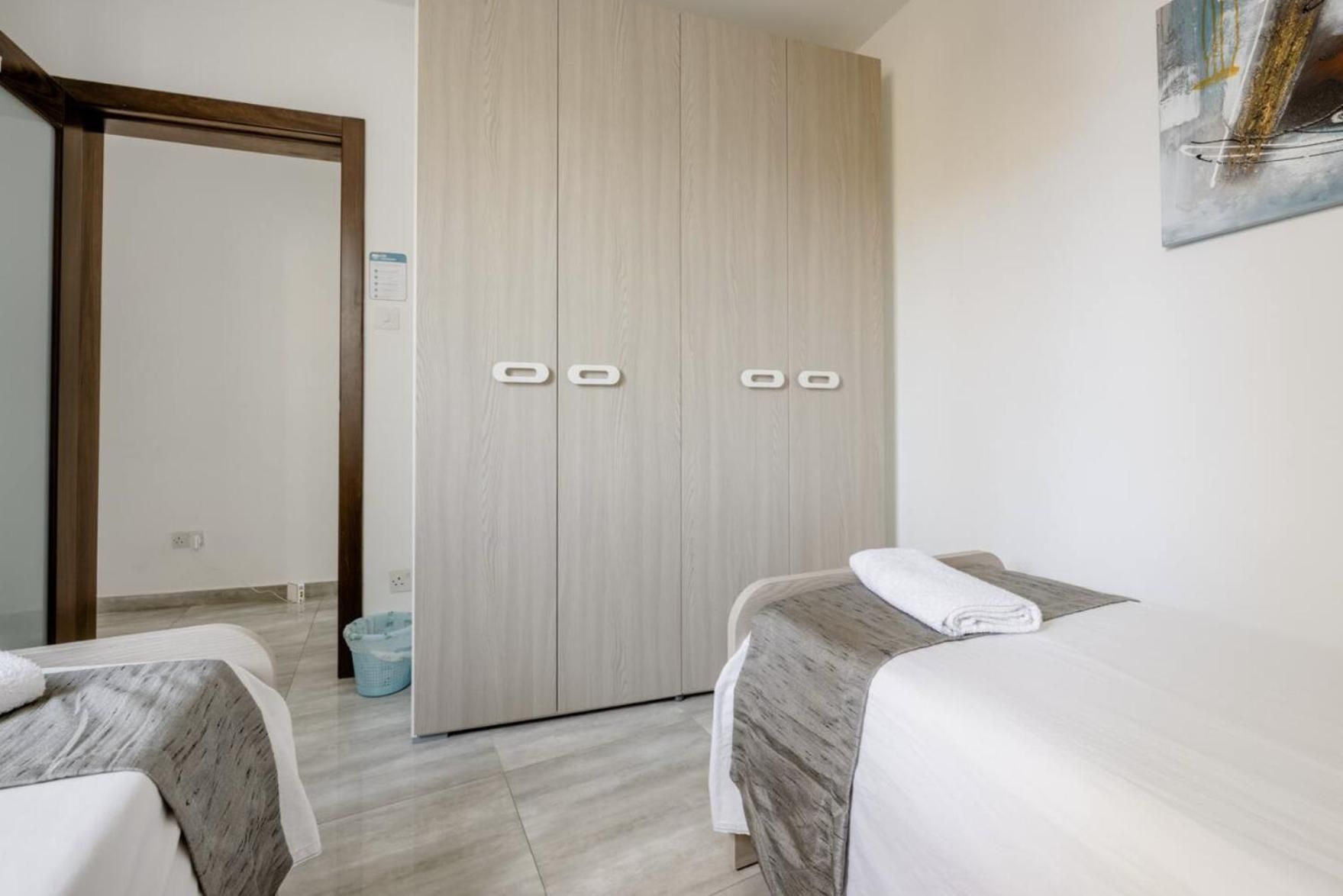Ein Hotelzimmer mit zwei Betten, einem Kleiderschrank und einem Papierkorb.