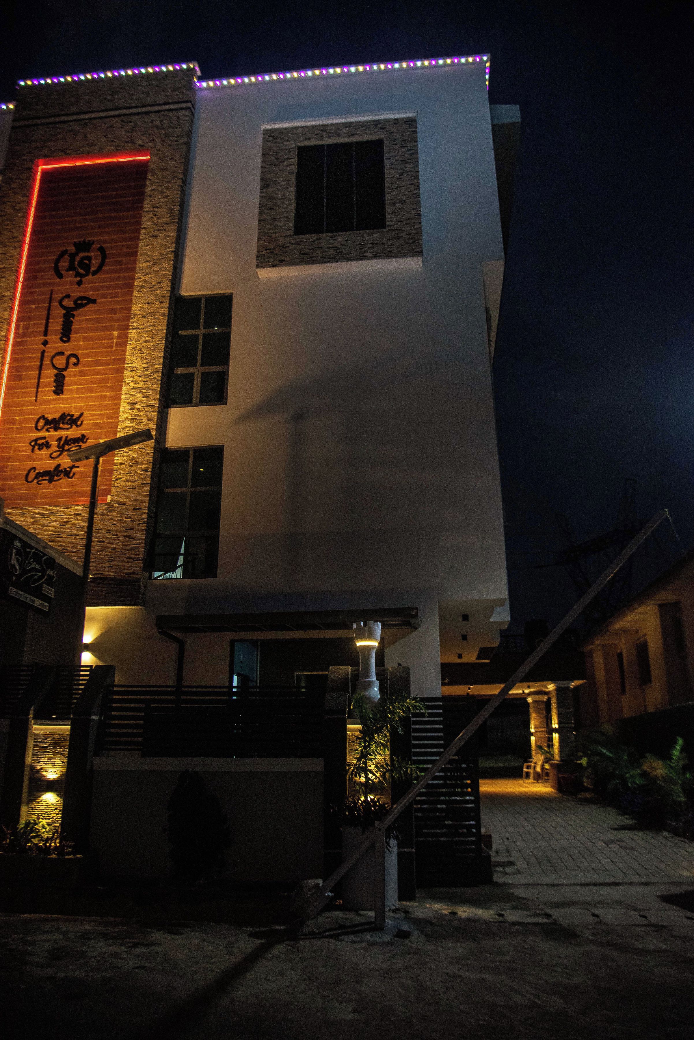 A modern building with a prominent sign on the side, a staircase leading to the entrance, and a well-lit entrance area.