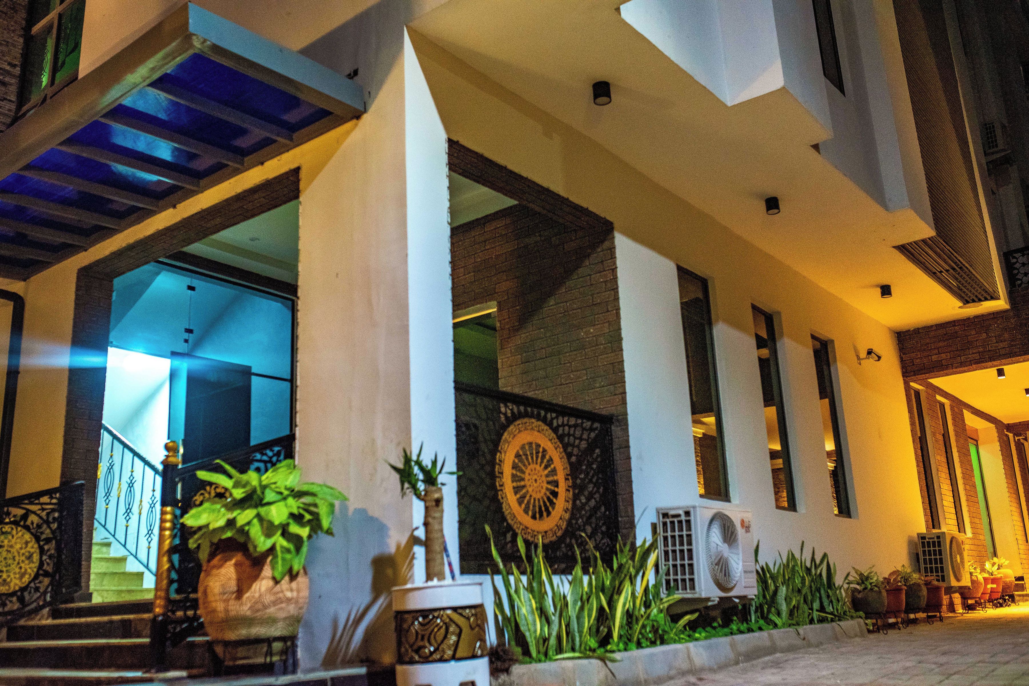A hotel entrance with a staircase, potted plants, and a decorative wall.