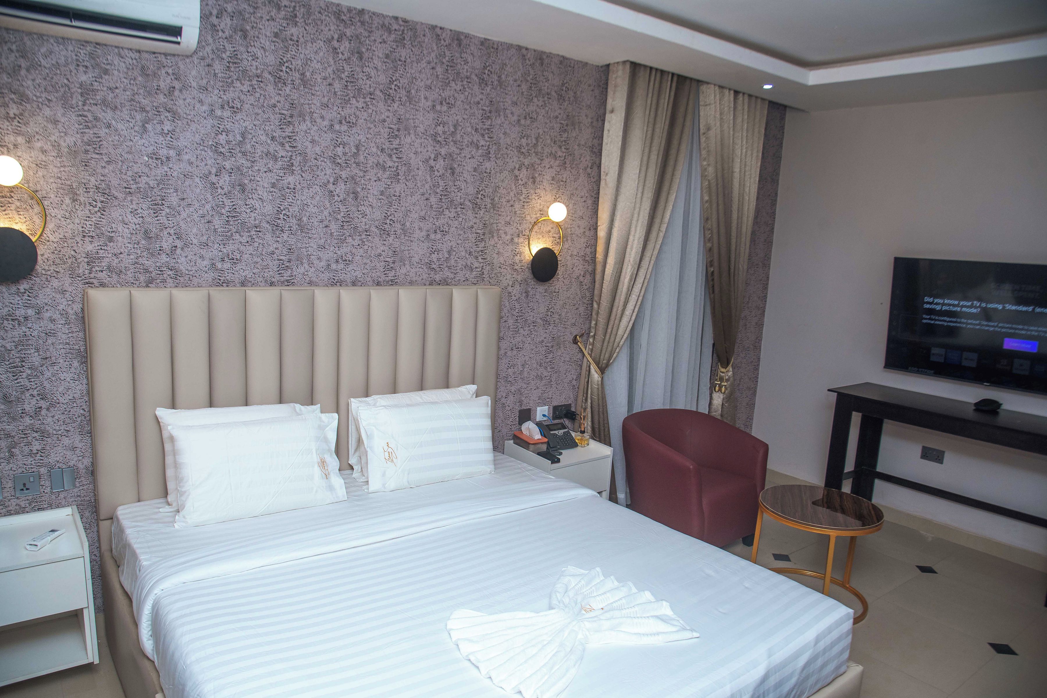 A hotel room with a bed, a TV, a desk, and a chair.